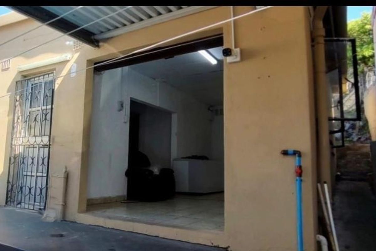 Rear exterior view of the property showing a covered entrance, security gate, and exposed exterior wall finishes.