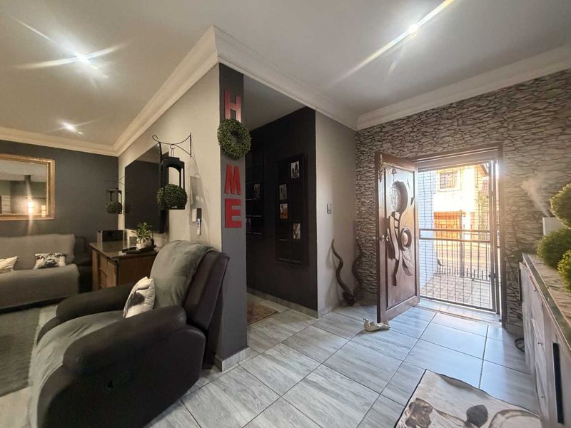 Entrance area featuring tiled flooring, decorative stone wall accents, and a carved wooden front door with an integrated security gate.