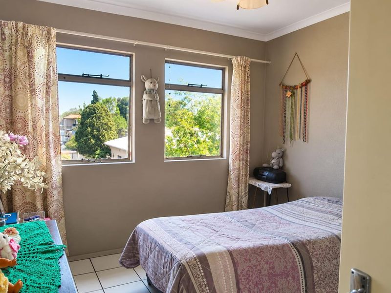 A bedroom featuring tiled flooring and dual windows providing natural light and views of the surrounding neighborhood.