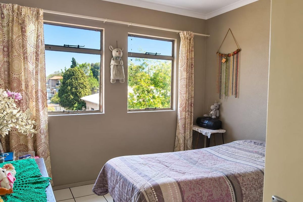 A bedroom featuring tiled flooring and dual windows providing natural light and views of the surrounding neighborhood.