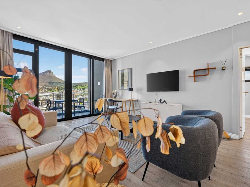 Modern living room featuring laminate flooring, recessed lighting, and large sliding glass doors opening to a balcony with mountain views.