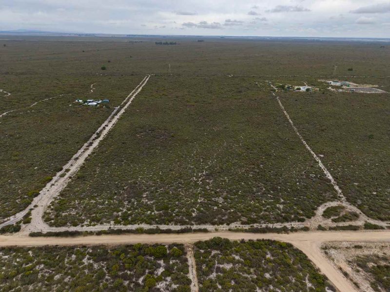 An aerial view of a large, undeveloped agricultural land parcel featuring natural vegetation and dirt access roads.