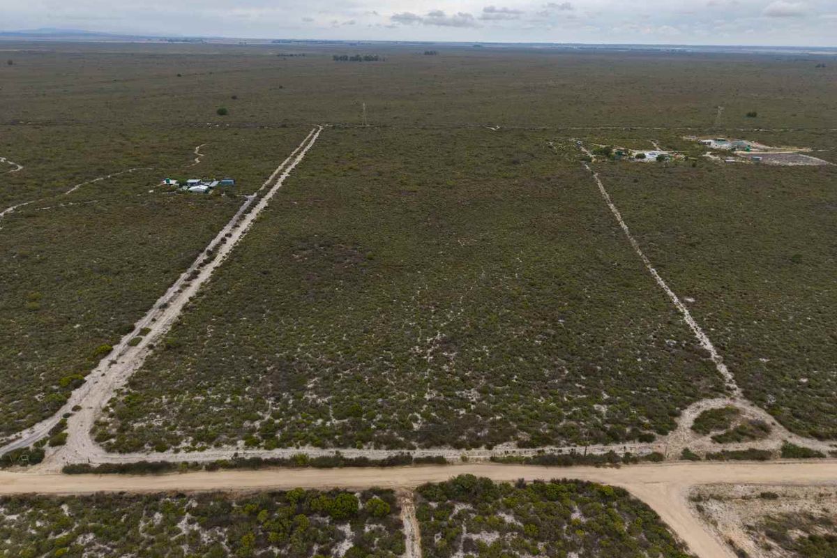 An aerial view of a large, undeveloped agricultural land parcel featuring natural vegetation and dirt access roads.