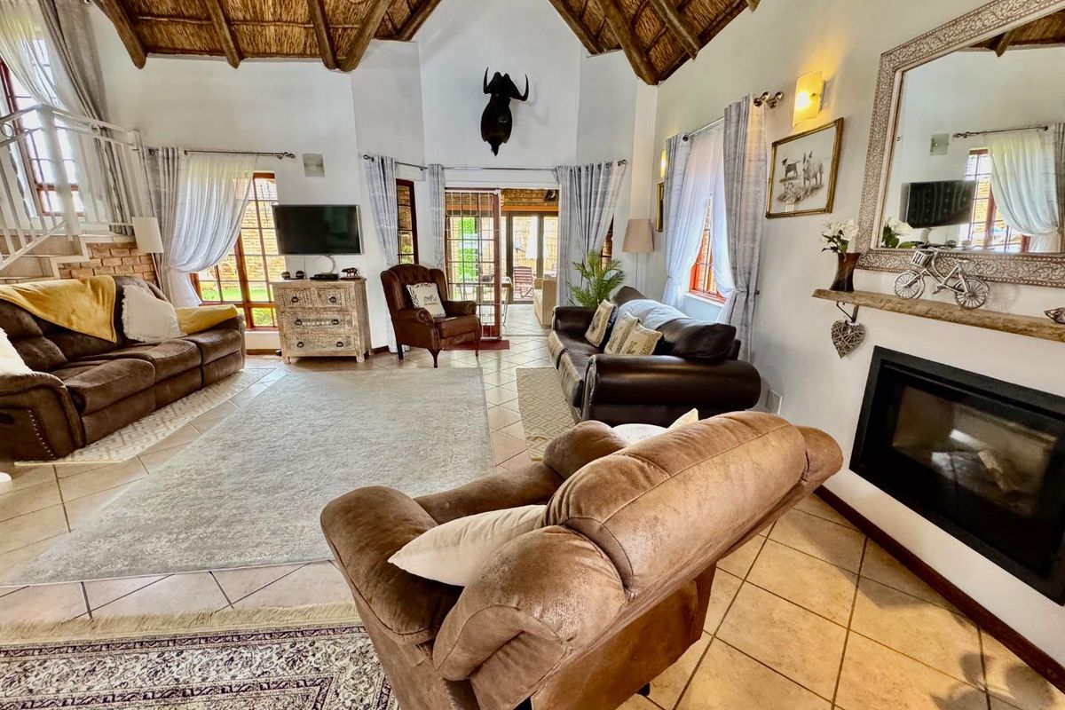 Spacious living room featuring a high vaulted thatched ceiling, tiled flooring, and a built-in fireplace, creating a warm and inviting atmosphere.