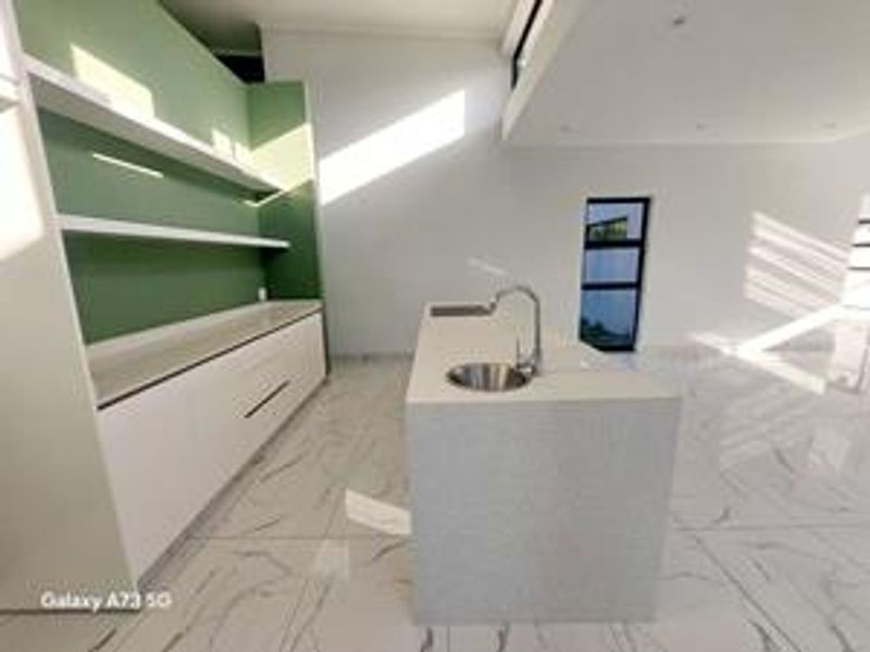 Modern kitchen featuring a central island with an undermount sink, sleek white cabinetry, open shelving, and polished marble-look floor tiles.