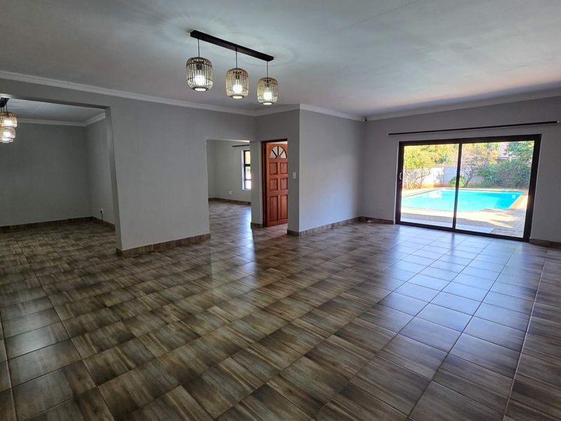 Spacious open-plan living area featuring neutral walls, tiled flooring, and large sliding glass doors providing direct access to the outdoor pool area.