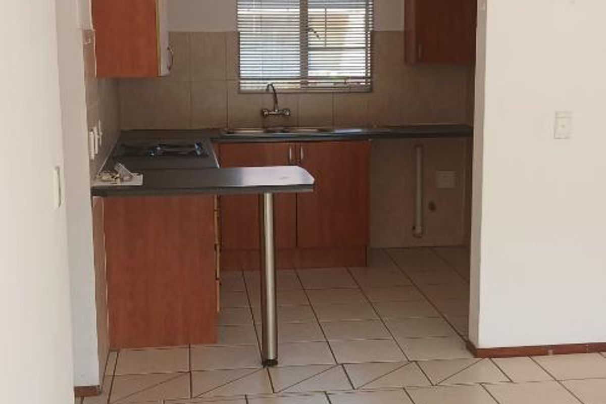 A functional kitchen featuring laminate cabinetry, tiled flooring, and a built-in hob, offering a clean and practical space ready for updates.