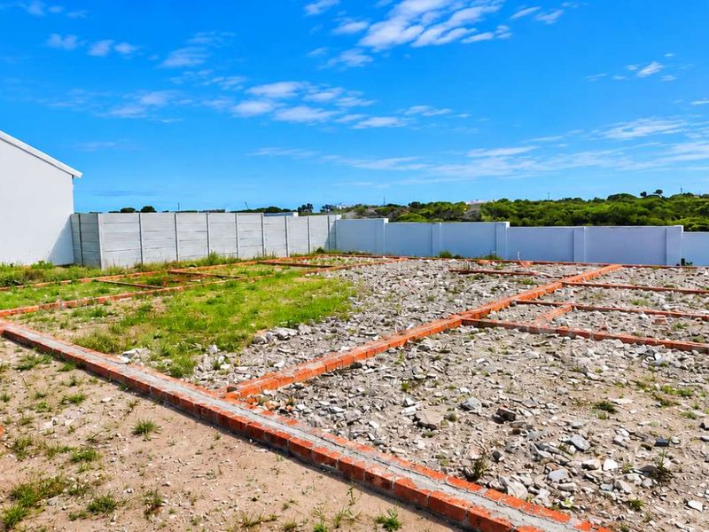 A residential plot featuring an exposed brick foundation and perimeter boundary wall, ready for further development.