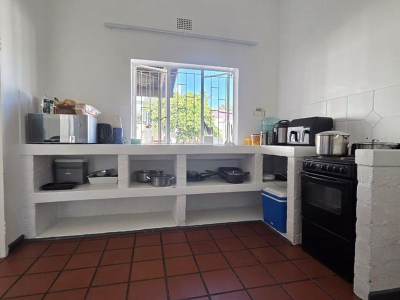 A functional kitchen featuring built-in masonry shelving, tiled flooring, and a freestanding oven, offering a basic layout with potential for modernization.