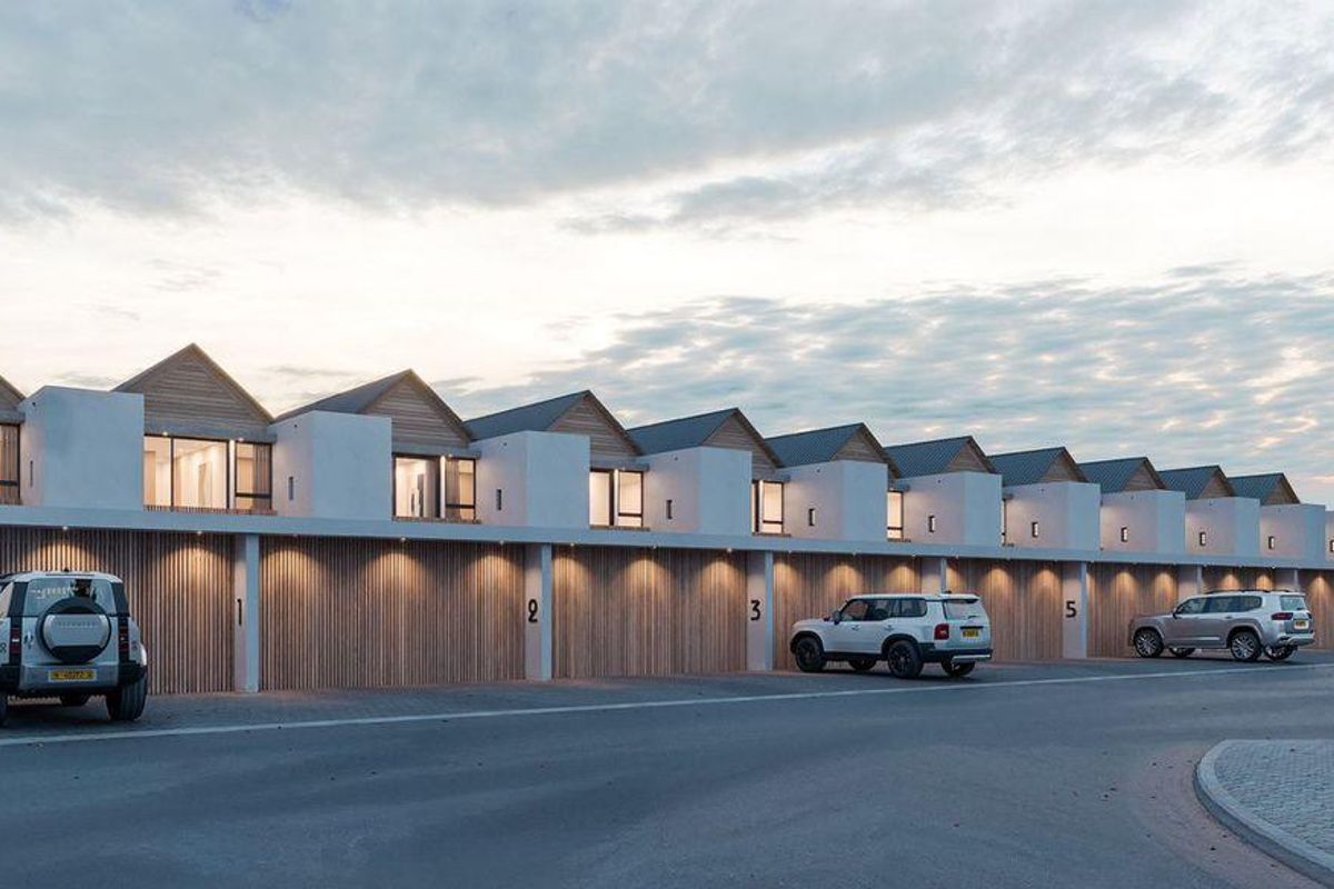 A modern row of townhouses featuring timber-clad garage doors, pitched roofs, and integrated exterior lighting, showcasing a contemporary architectural design.