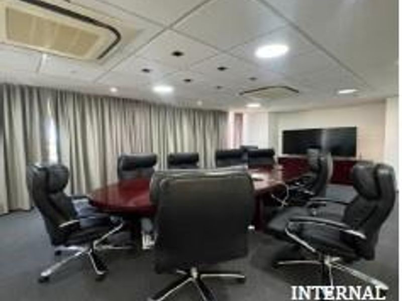 A professional office boardroom featuring a large conference table, integrated ceiling lighting, and built-in air conditioning units.