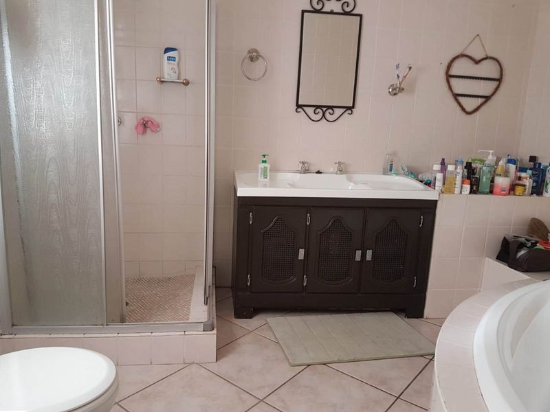 A functional bathroom featuring a shower enclosure, double basin vanity, and built-in bathtub with neutral wall and floor tiling.