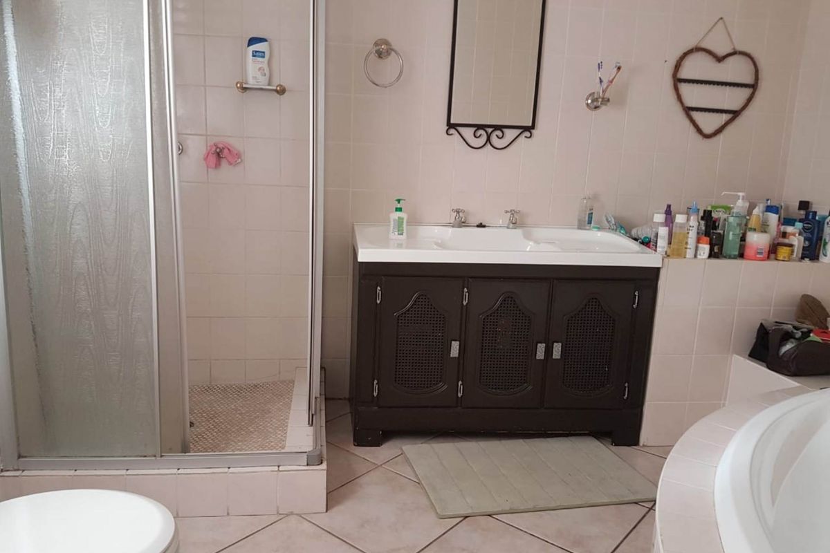 A functional bathroom featuring a shower enclosure, double basin vanity, and built-in bathtub with neutral wall and floor tiling.