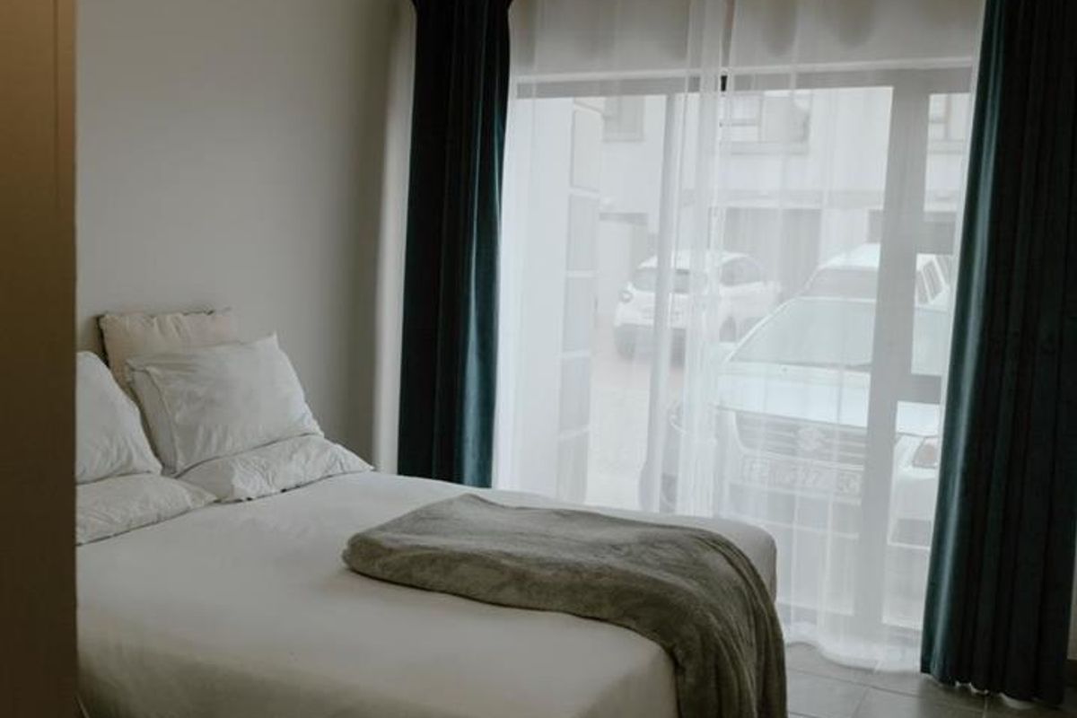 A bedroom featuring tiled flooring and a large sliding glass door that provides natural light and access to the exterior.