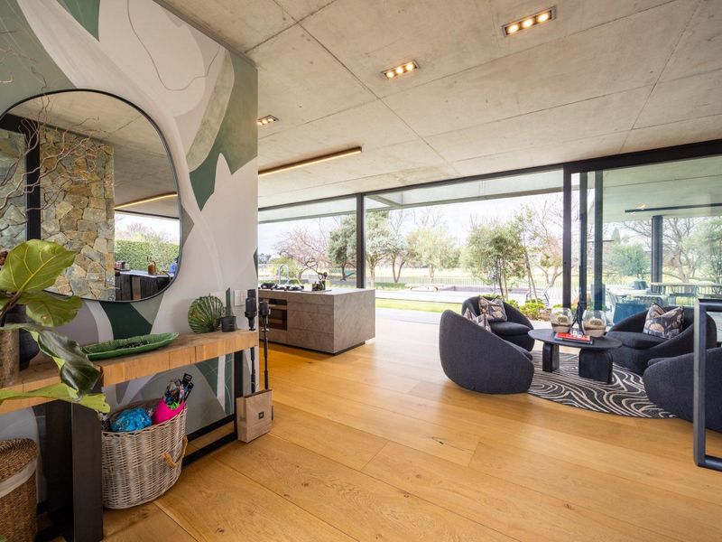 Modern open-plan living area featuring exposed concrete ceilings, hardwood floors, and expansive sliding glass doors that seamlessly connect to the outdoor space.
