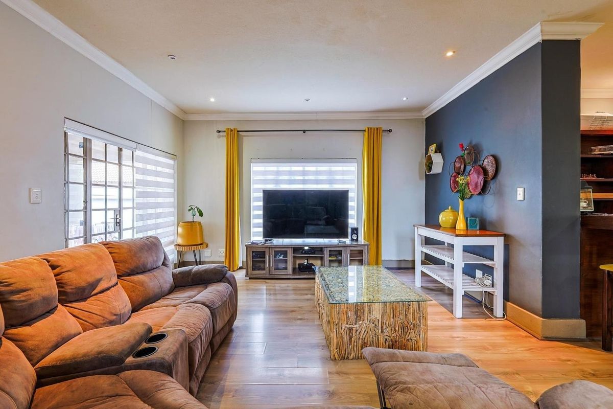 A comfortable living room featuring wood-look flooring, recessed downlighting, and a striking dark accent wall, creating a warm and inviting atmosphere.