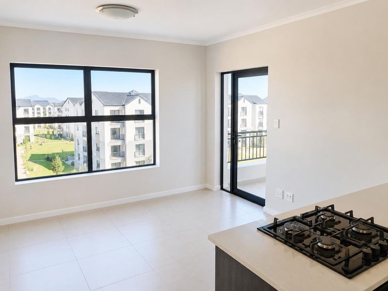 Modern open-plan living area featuring tiled floors, a gas hob, and direct access to a private balcony with views of the complex.