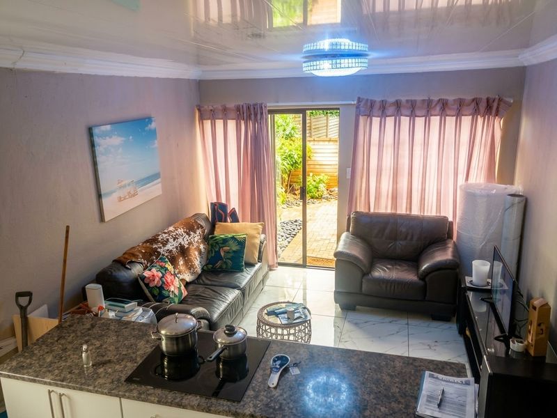 Open-plan living area featuring tiled floors, a glossy ceiling, and a sliding door providing direct access to the rear patio area.