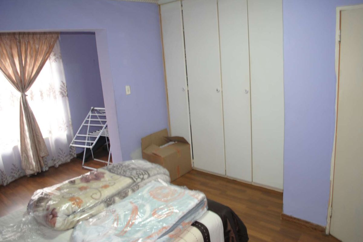 A bedroom featuring built-in cupboards with white doors and laminate flooring, offering functional storage space.