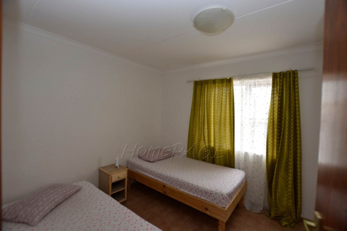 A functional bedroom featuring tiled flooring and a window with curtain fixtures.