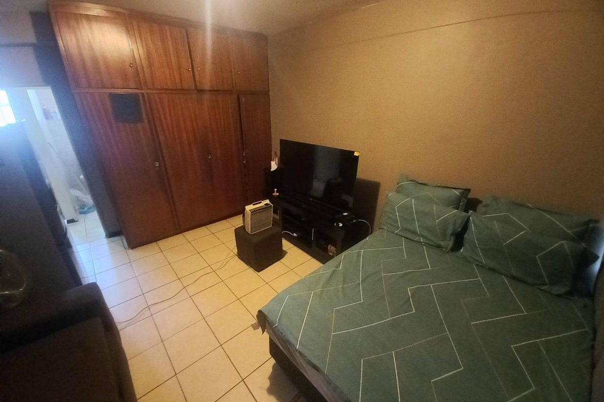 A bedroom featuring built-in wooden cupboards and tiled flooring, providing functional storage space within the apartment.