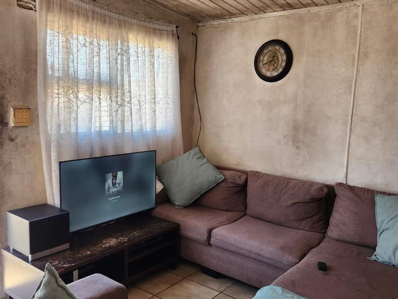A living room featuring tiled flooring and a timber panel ceiling, currently showing significant wear and staining on the wall surfaces.