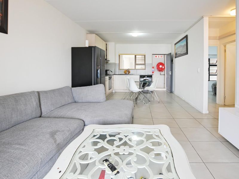 Open-plan living area featuring tiled flooring and a functional kitchen space with built-in cabinetry, providing a versatile layout for modern apartment living.