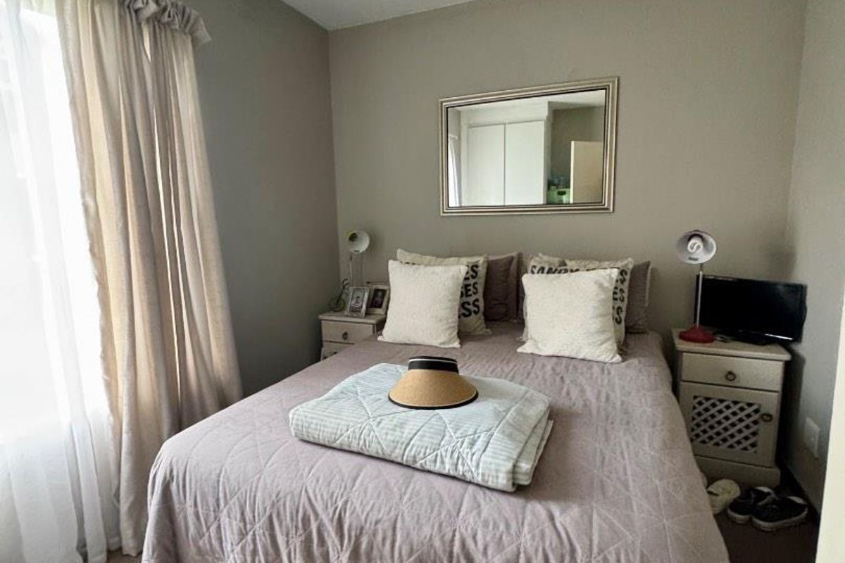 A cozy bedroom featuring neutral wall tones, carpeted flooring, and window treatments, providing a comfortable and functional sleeping space.