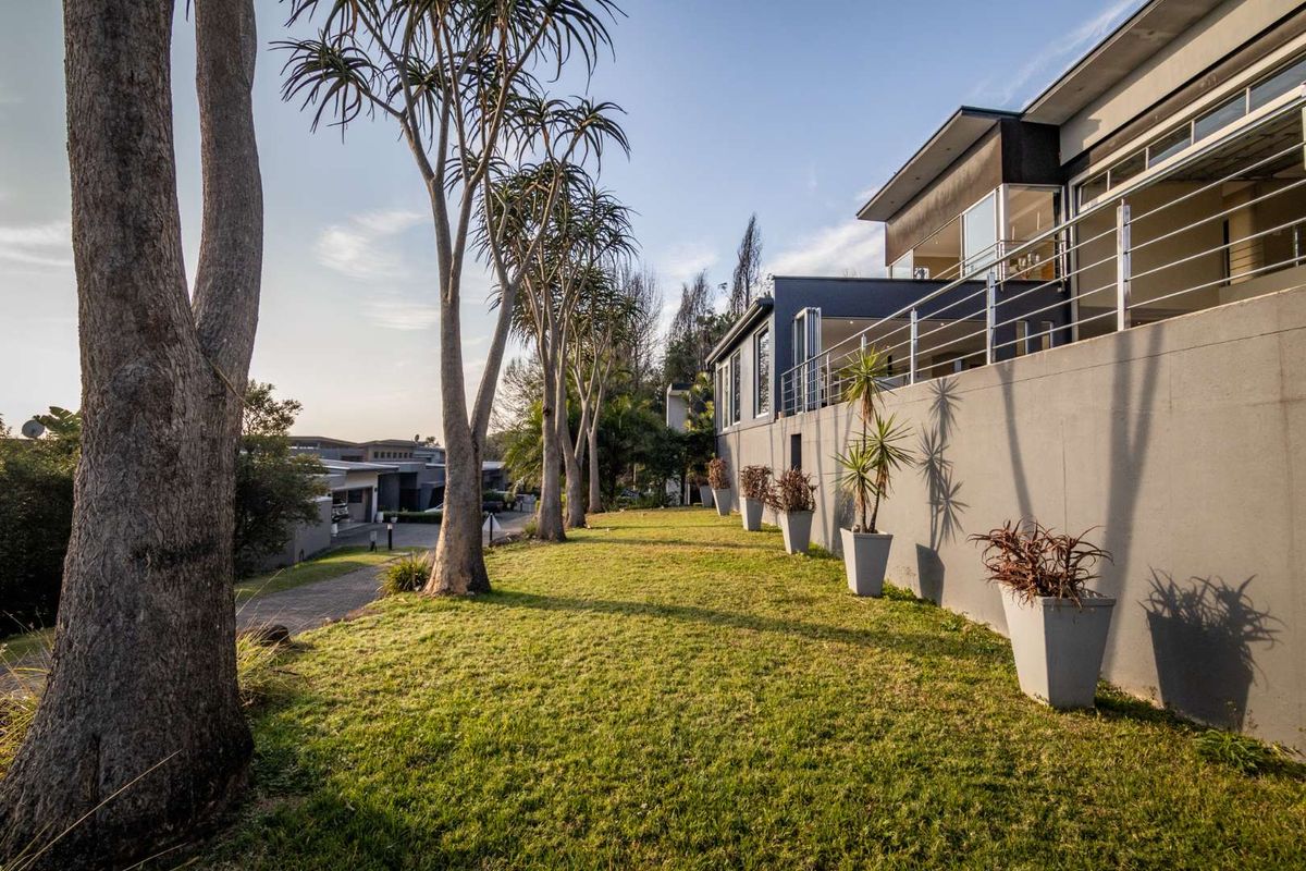 A well-maintained rear garden featuring a retaining wall, stainless steel balustrades, and mature trees, providing a clean outdoor space for the property.