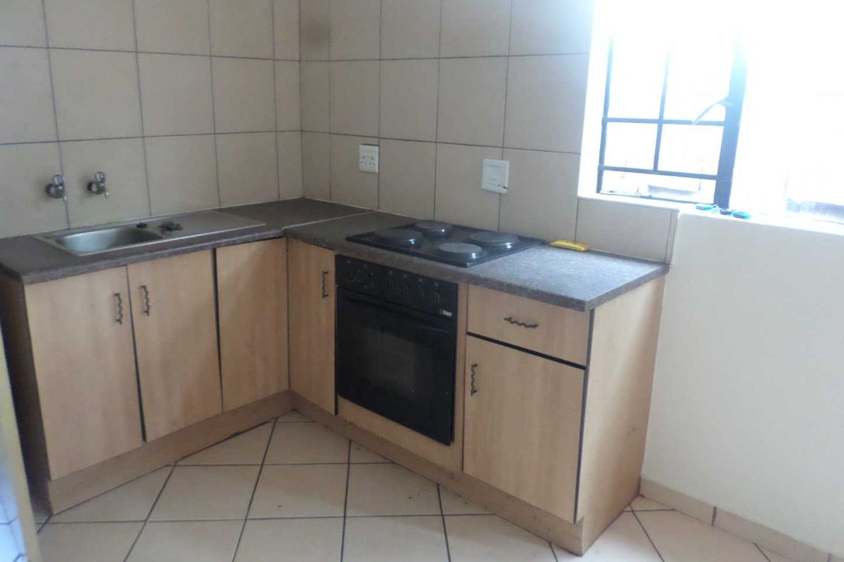 A functional kitchen featuring built-in cabinetry, laminate countertops, a stainless steel sink, and a built-in oven with an electric hob.