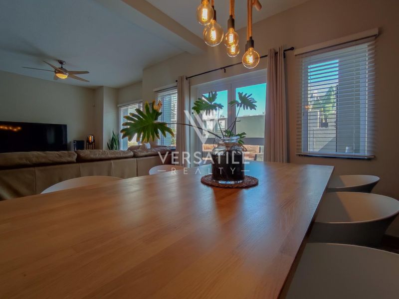 Open plan living and dining area featuring modern pendant lighting, ceiling fan, and sliding glass doors leading to the exterior.