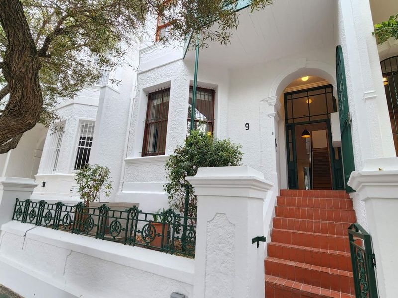 Charming front facade featuring a classic arched entrance, terracotta tiled steps, and secure wrought iron fencing, showcasing traditional architectural character.