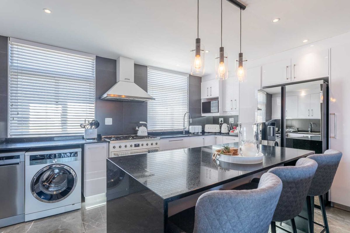 Modern kitchen featuring granite countertops, high-end cabinetry, integrated appliances, and a central island with pendant lighting, offering a sleek and functional culinary space.