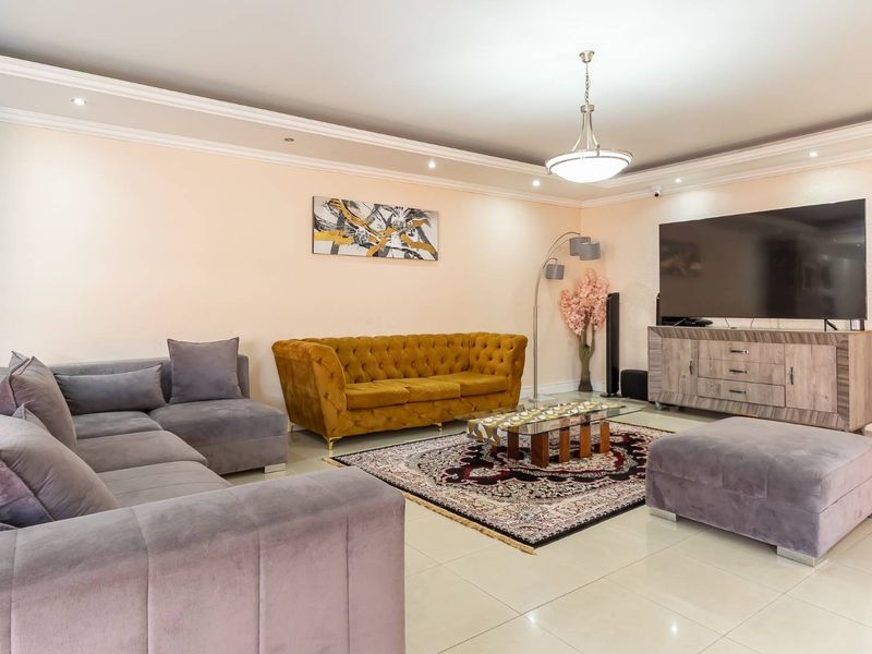 Spacious living room featuring neutral tiled flooring, crown molding, and recessed ceiling lighting, creating a comfortable and well-maintained living space.