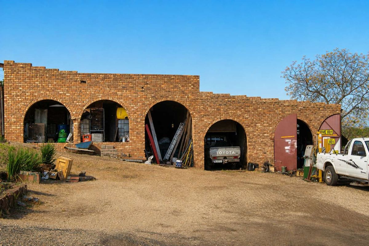 A rustic brick outbuilding featuring multiple arched bays, currently utilized as a garage and storage area on the farm property.