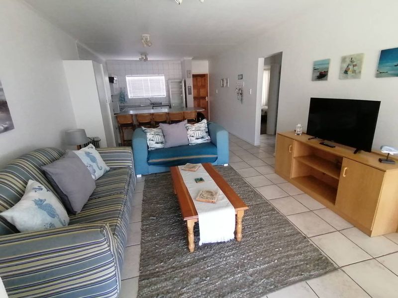 Open plan living area featuring tiled flooring and a breakfast bar kitchen counter, creating a functional and connected living space.