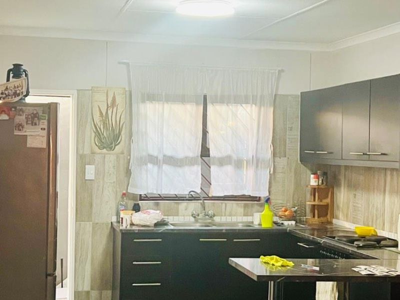 A functional kitchen featuring dark cabinetry, tiled backsplash, and a compact breakfast bar area, providing essential storage and workspace.