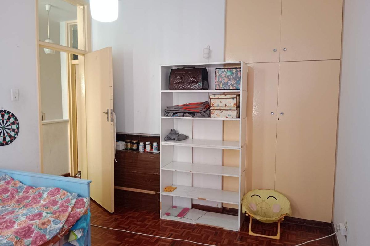 A bedroom featuring built-in floor-to-ceiling storage cupboards and traditional parquet wood flooring.