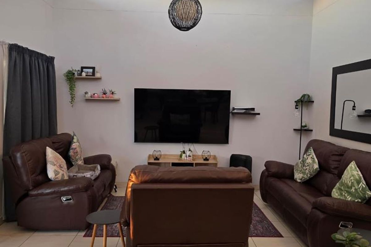 Spacious living room featuring a high vaulted ceiling with skylights, tiled flooring, and a wall-mounted television setup.