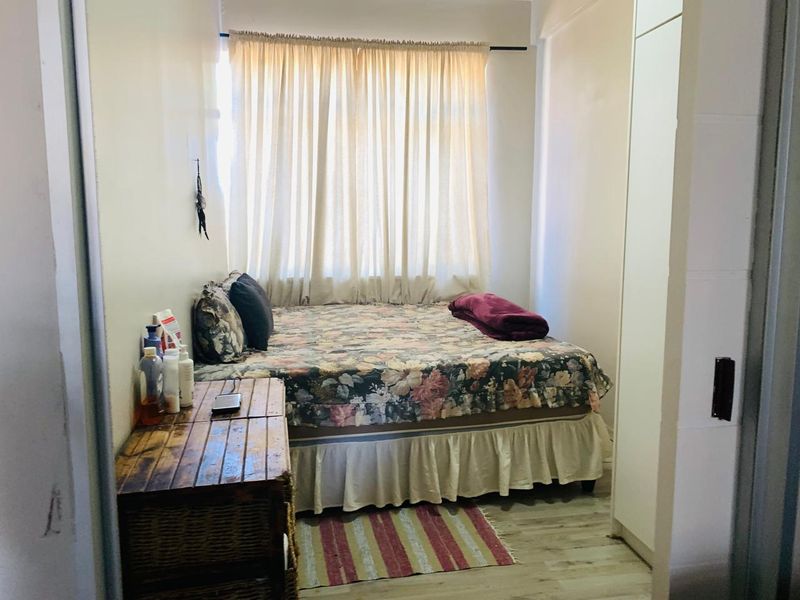 A compact bedroom featuring laminate flooring and a built-in wardrobe, providing functional storage space.