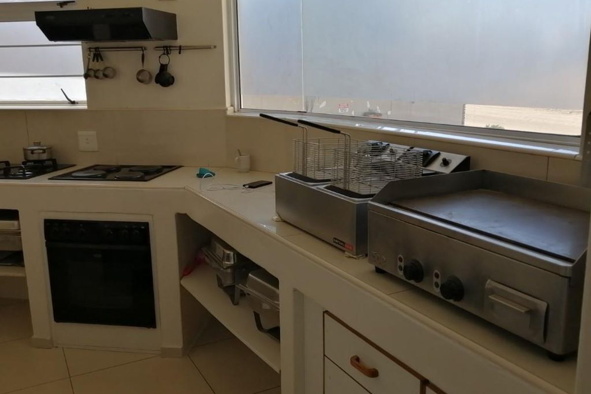 A functional kitchen area featuring built-in cabinetry, a gas hob, an integrated oven, and an extractor fan with tiled flooring.