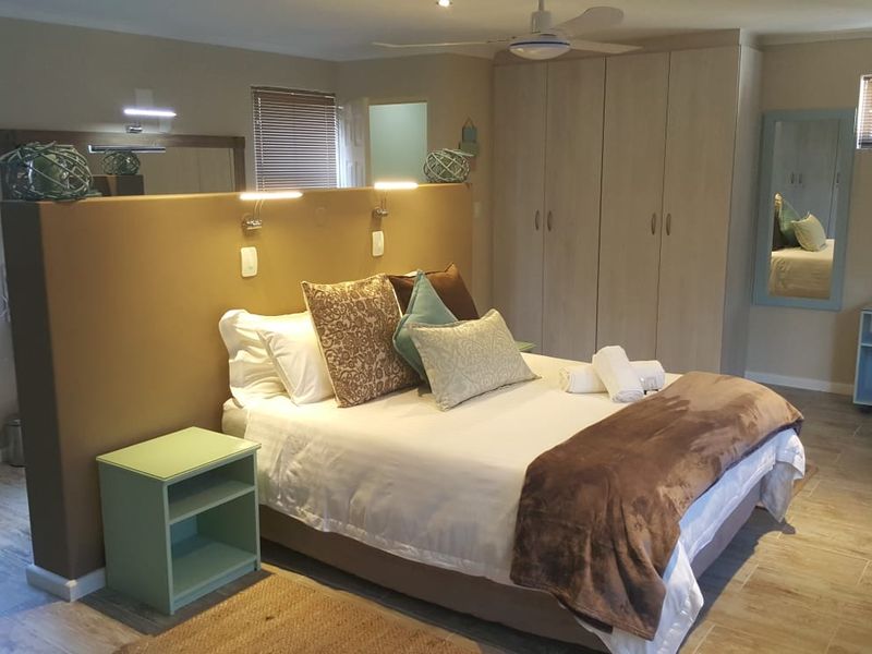 Spacious bedroom featuring built-in cupboards, tiled flooring, ceiling fan, and a central partition wall with integrated reading lights.
