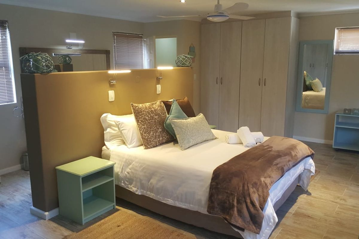 Spacious bedroom featuring built-in cupboards, tiled flooring, ceiling fan, and a central partition wall with integrated reading lights.