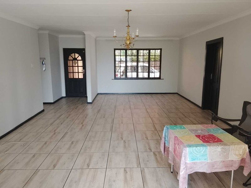 Spacious, open-plan living area featuring neutral tiled flooring, coved ceilings, and a classic chandelier, providing a versatile blank canvas for interior design.