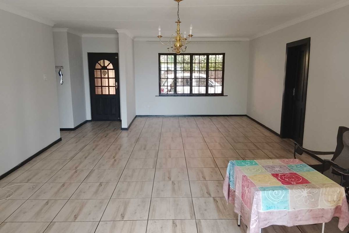 Spacious, open-plan living area featuring neutral tiled flooring, coved ceilings, and a classic chandelier, providing a versatile blank canvas for interior design.
