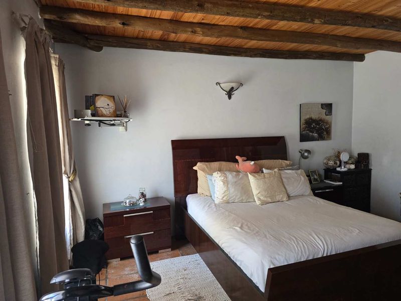A cozy bedroom featuring rustic exposed timber ceiling beams and traditional terracotta floor tiles, creating a warm and inviting atmosphere.