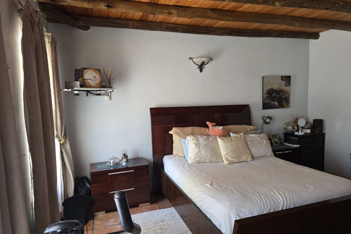 A cozy bedroom featuring rustic exposed timber ceiling beams and traditional terracotta floor tiles, creating a warm and inviting atmosphere.