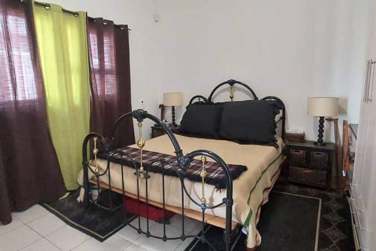 A bedroom featuring built-in wardrobes and tiled flooring, providing a functional space with natural light from the window.