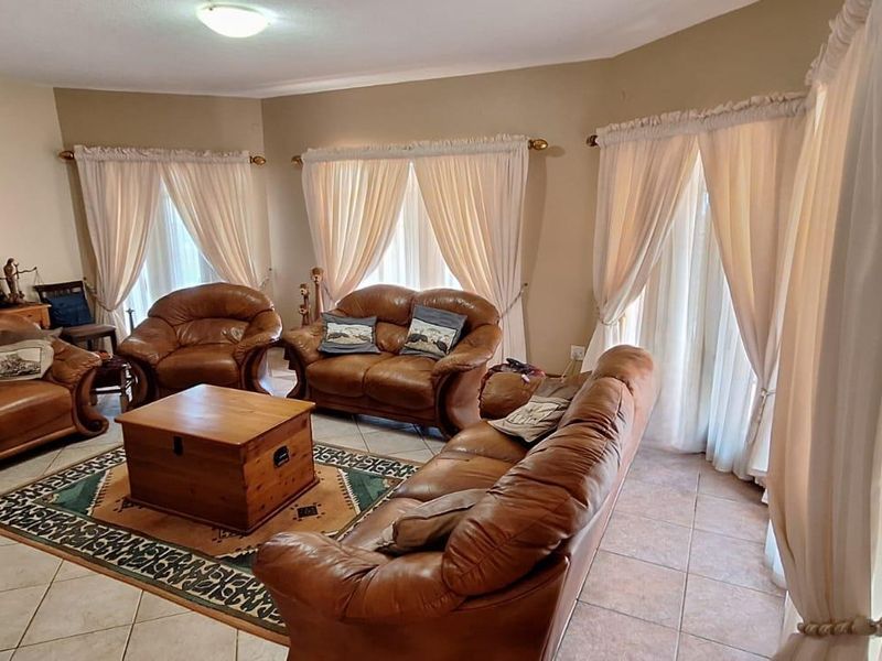 A spacious living room featuring tiled flooring and large windows with curtain treatments, offering a comfortable and functional layout.