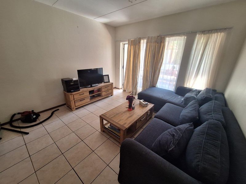 A living room featuring tiled flooring and a sliding glass door providing access to the outdoor area.